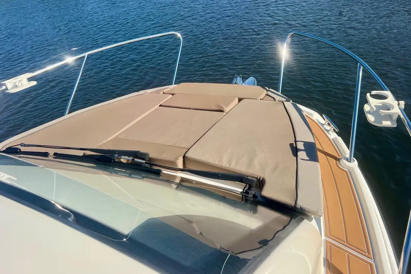 Slide: The Image of 2024 Bayliner Trophy T25 Explorer boat deck with cushioned seating on calm water. - 21