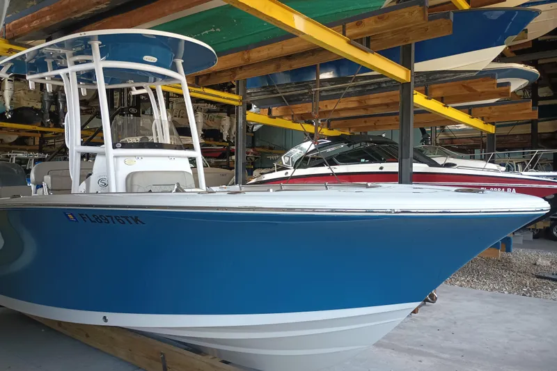 Slide: The Image of 2023 Sportsman Heritage 231 Center Console boat in storage, blue hull, white deck. - 2