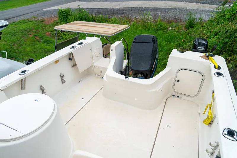 Slide: The Image of 2002 Bayliner 2302 Trophy Walkaround boat interior with motor, docked on grassy area. - 10