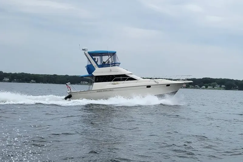 The Image of 1990 Silverton 37 Convertible yacht cruising on a lake with scenic shoreline. - 0