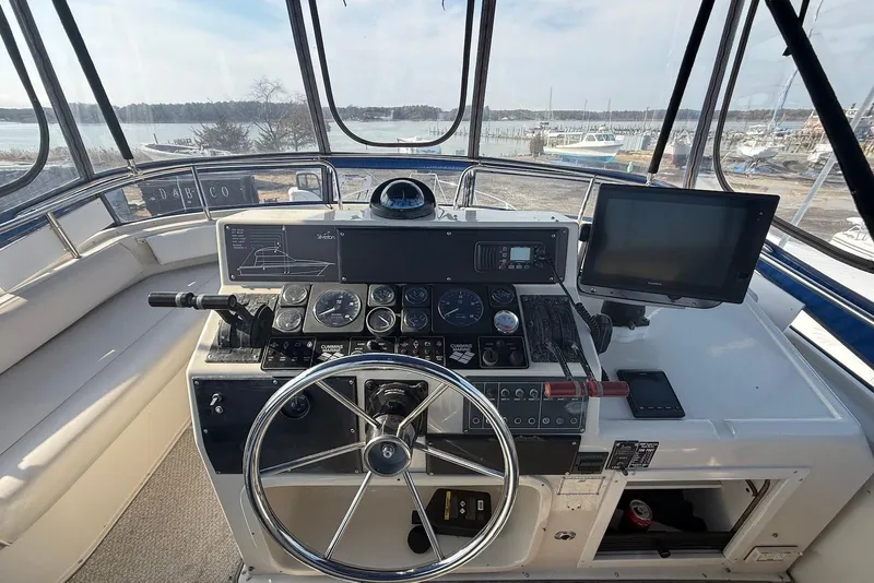 Slide: The Image of 1990 Silverton 37 Convertible boat helm with steering wheel, gauges, and navigation equipment. - 12