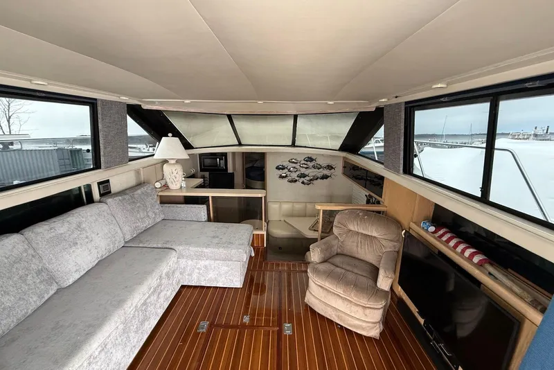 Slide: The Image of Interior of a 1990 Silverton 37 Convertible yacht with cozy seating and wood flooring. - 19