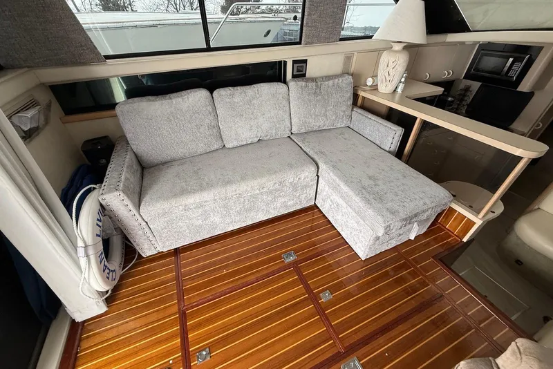 Slide: The Image of Luxurious interior of 1990 Silverton 37 Convertible yacht with plush gray sofa and wooden flooring. - 20