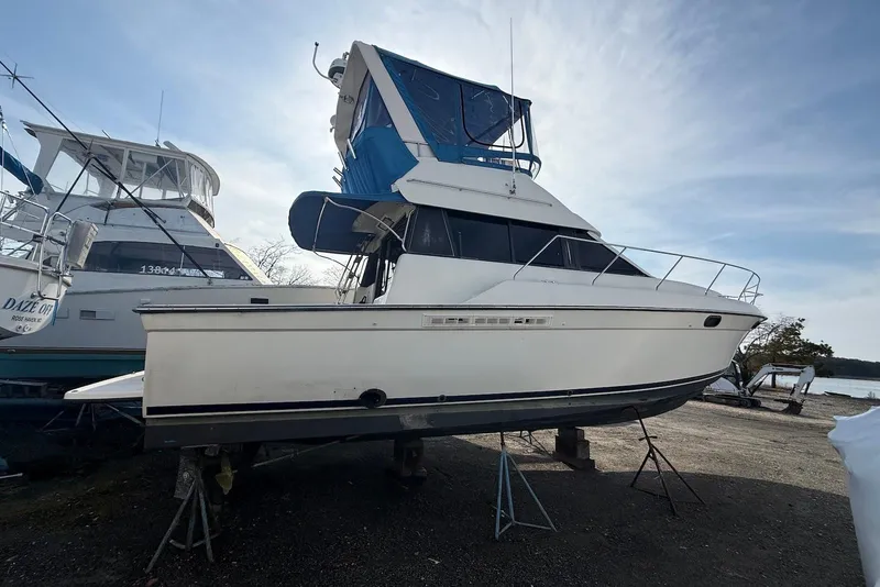 Slide: The Image of 1990 Silverton 37 Convertible boat on stands, with blue canopy, docked outdoors. - 4