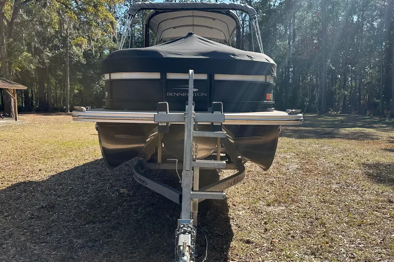 Slide: The Image of 2023 Bennington LX 26 Swingback pontoon boat on trailer in wooded area. - 16