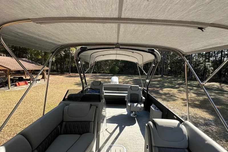 Slide: The Image of 2023 Bennington LX 26 Swingback pontoon boat interior with canopy, featuring luxurious seating. - 8