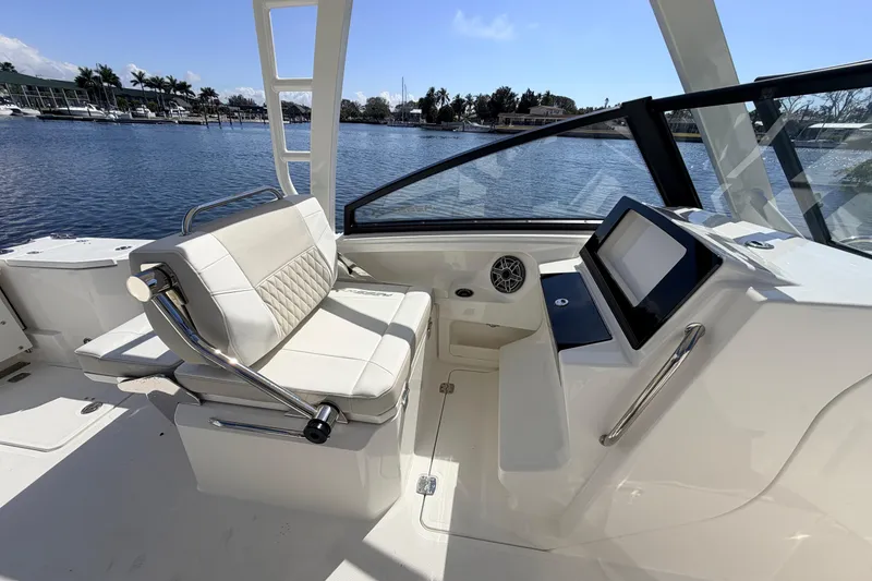 Slide: The Image of 2026 World Cat 265 DC-X boat interior with seating and control panel, docked by the water. - 13
