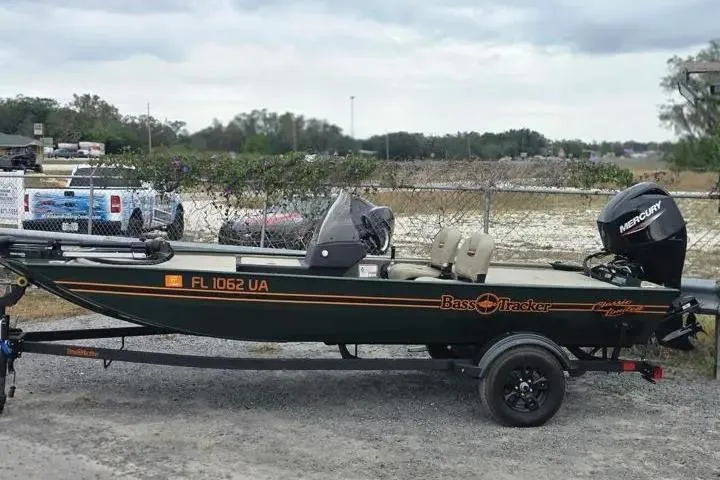 Slide: The Image of 2025 Bass Tracker III Classic boat with Mercury engine on trailer, parked outdoors. - 10
