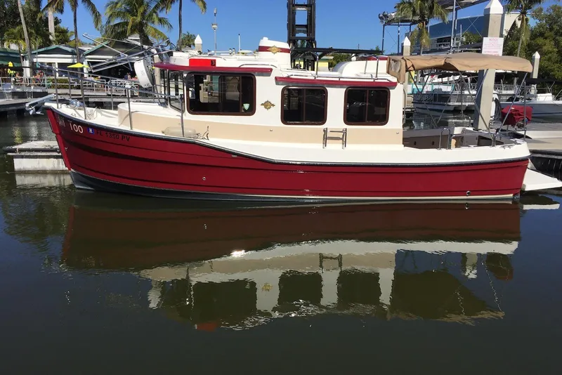 The Image of 2012 Ranger Tugs R-27 boat docked in a marina, reflecting on calm water. - 0