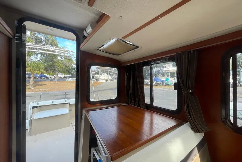 Slide: The Image of Interior view of 2012 Ranger Tugs R-27 boat with wooden table and windows. - 13