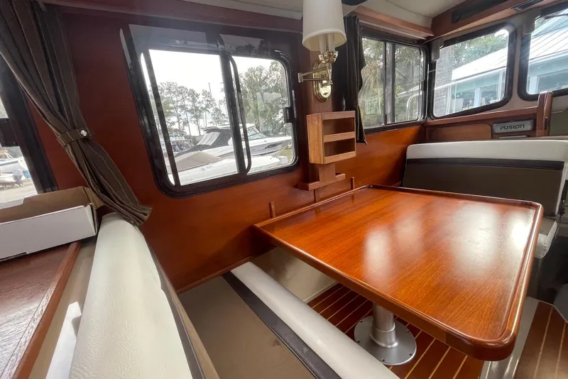 Slide: The Image of Interior of 2012 Ranger Tugs R-27 with wooden table and seating area. - 14