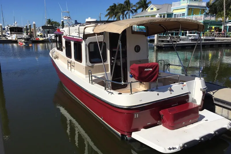 Slide: The Image of 2012 Ranger Tugs R-27 boat docked at marina, featuring red and white exterior. - 2