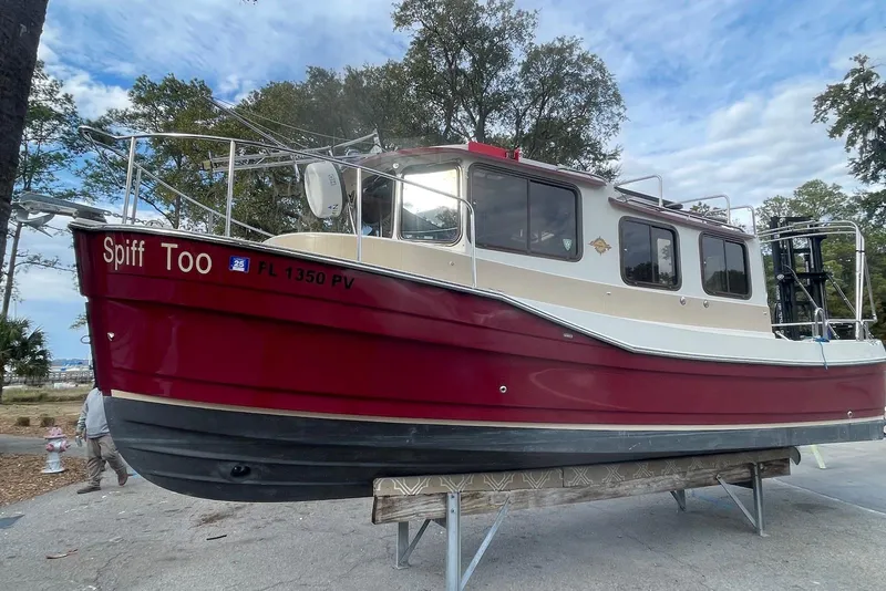 Slide: The Image of 2012 Ranger Tugs R-27 boat, red and beige, on a trailer, outdoors. - 3