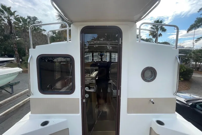 Slide: The Image of 2012 Ranger Tugs R-27 boat exterior with door and windows, docked outdoors. - 9