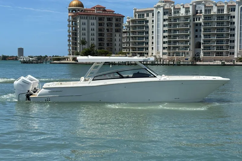 Slide: The Image of 2026 World Cat 400 DC-X Island boat cruising near luxury waterfront buildings. - 10