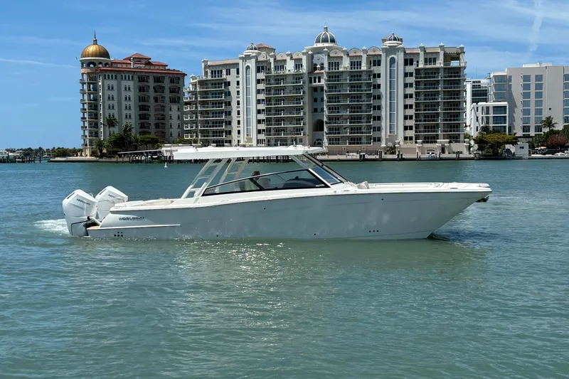 Slide: The Image of 2026 World Cat 400 DC-X Island boat cruising near luxury waterfront buildings. - 15