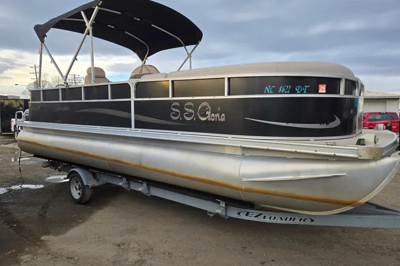 The Image of 2012 Berkshire 230 CL LSR pontoon boat on trailer, black exterior, canopy, labeled "S.S. Gloria." - 0