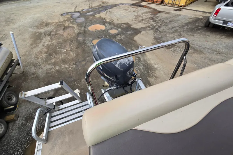 Slide: The Image of 2012 Berkshire 230 CL LSR boat with outboard motor and ladder on a gravel surface. - 12