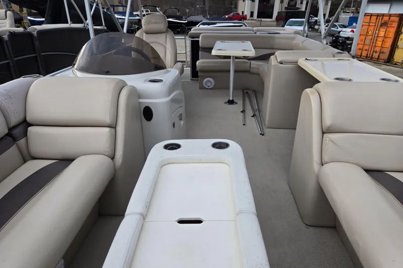Slide: The Image of 2012 Berkshire 230 CL LSR pontoon boat interior with beige seating and table. - 13