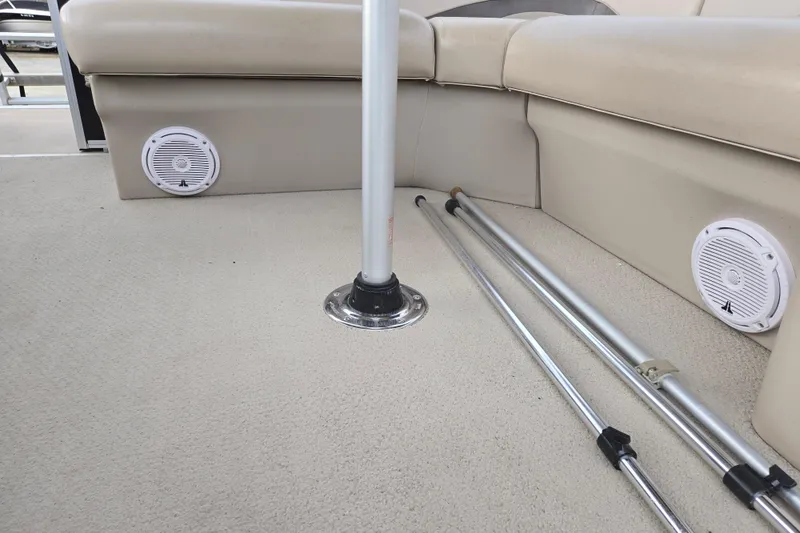 Slide: The Image of 2012 Berkshire 230 CL LSR boat interior with beige seating and mounted speakers. - 14