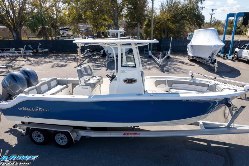 Slide: The Image of 2021 NauticStar 2602 Legacy boat on trailer, blue and white design, parked outdoors. - 45