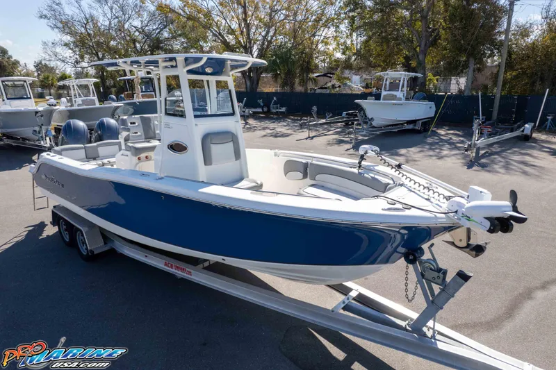 Slide: The Image of 2021 NauticStar 2602 Legacy boat on trailer, blue and white, parked outdoors. - 48
