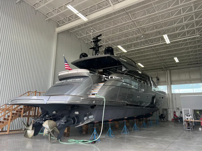 Slide: The Image of 2017 Pershing 92 Motor Yacht in a warehouse, elevated on stands, with visible propellers. - 10