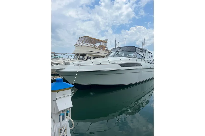 The Image of 1990 Carver 528 Montego yacht docked at marina under cloudy sky. - 1