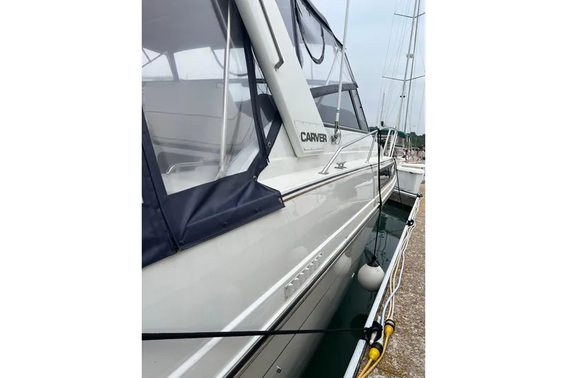 Slide: The Image of 1990 Carver 528 Montego yacht docked at marina, featuring sleek design and protective canopy. - 3