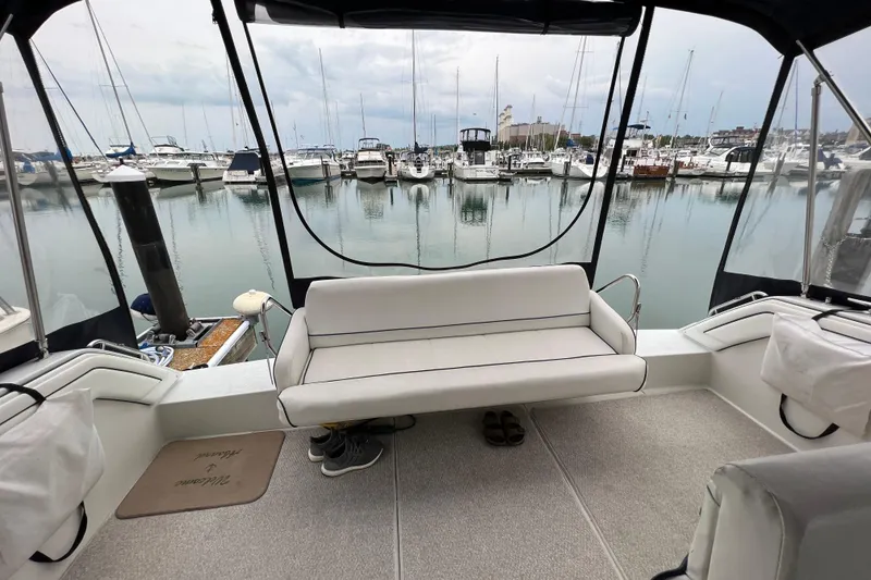 Slide: The Image of 1990 Carver 528 Montego yacht interior with marina view, featuring white seating and calm waters. - 6