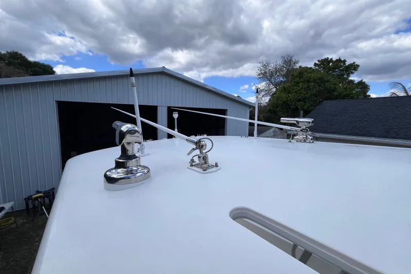 Slide: The Image of 2021 SeaVee 340B Open boat with antennas, parked near a metal building under cloudy sky. - 56