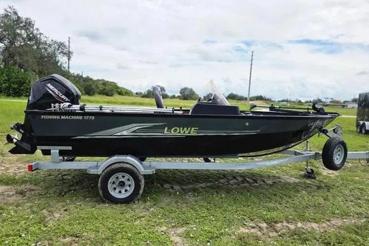 Slide: The Image of 2021 Lowe Fishing Machine 1775SC boat on trailer, parked on grassy area. - 25