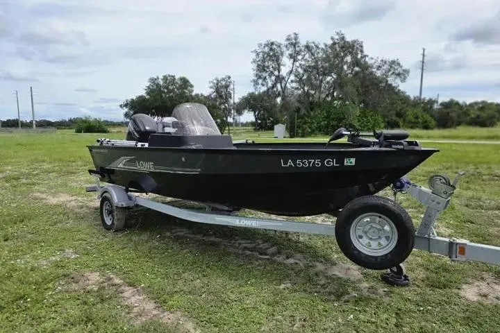 Slide: The Image of 2021 Lowe Fishing Machine 1775SC boat on trailer in grassy area. - 26