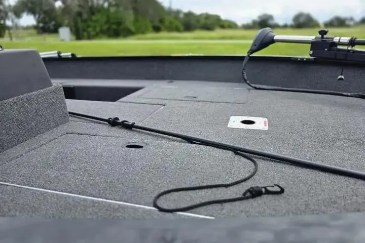 Slide: The Image of 2021 Lowe Fishing Machine 1775SC boat deck with fishing rod holder, grassy background. - 30