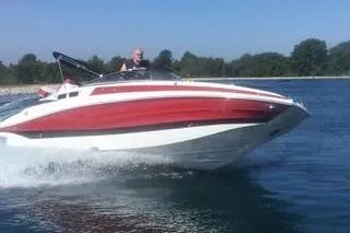 The Image of 2024 Crownline Eclipse E235 boat cruising on a lake with a clear blue sky. - 1