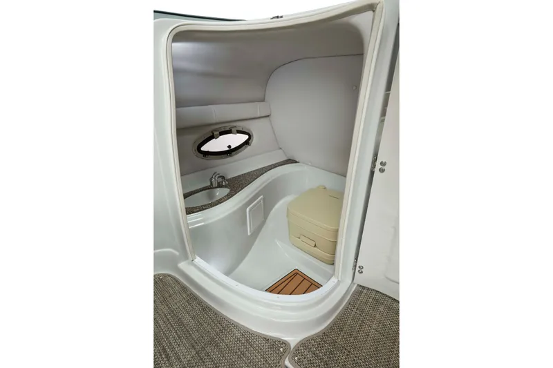 Slide: The Image of 2024 Crownline Eclipse E235 boat interior with compact bathroom and porthole window. - 7