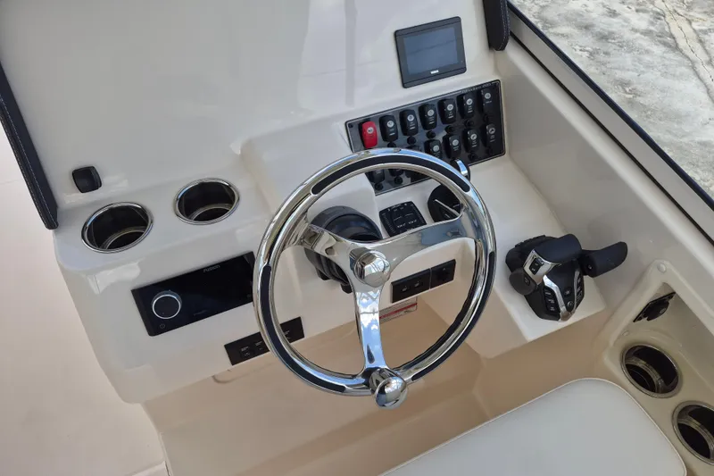 Slide: The Image of 2026 Grady-White Freedom 285 helm with steering wheel, controls, and cup holders. - 15