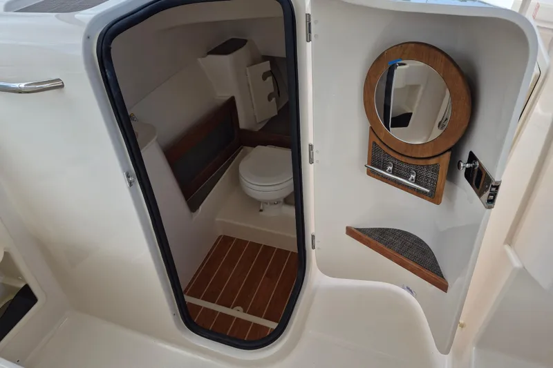 Slide: The Image of 2026 Grady-White Freedom 285 boat interior with compact bathroom and wooden accents. - 16
