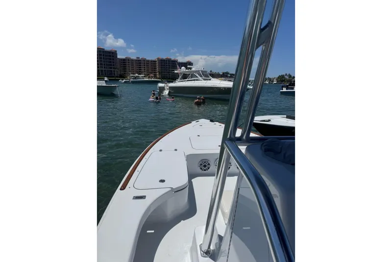 Slide: The Image of 2024 Billfish 24 boat on water with people swimming nearby, buildings in background. - 6