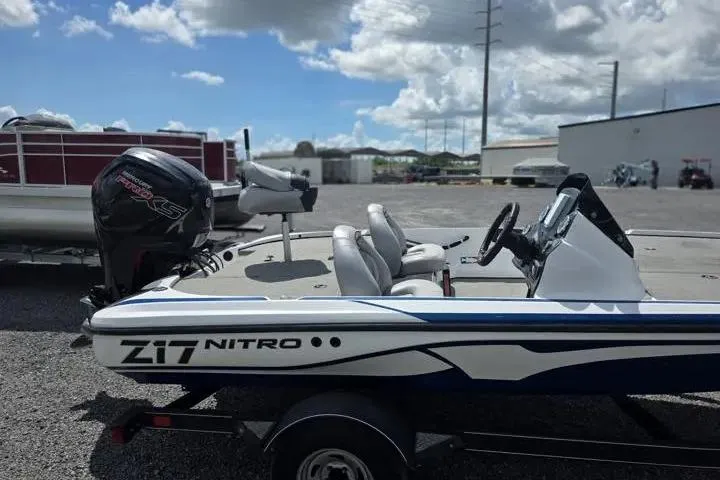 Slide: The Image of 2017 Nitro Z17 boat with outboard motor, parked outdoors under a cloudy sky. - 6