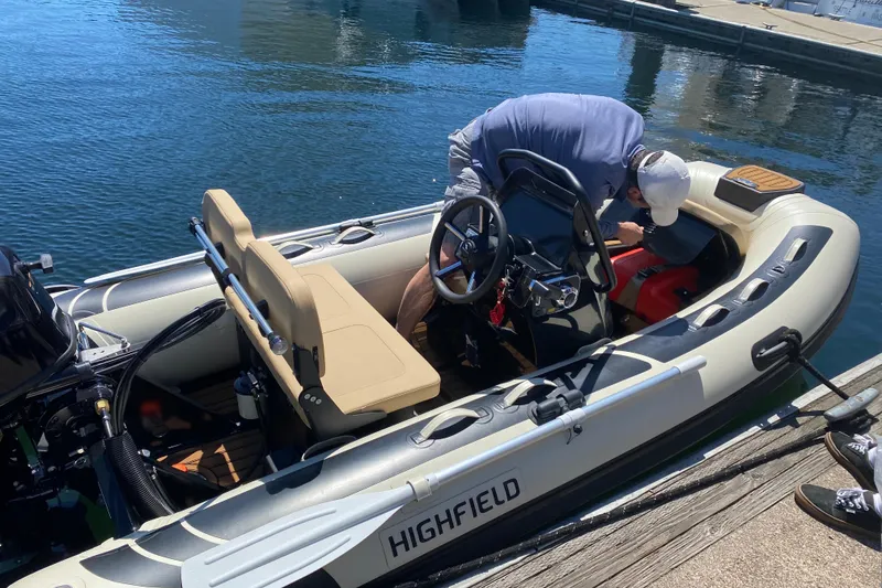 Slide: The Image of Man working on a Highfield inflatable boat at a dock, sunny day. - 103