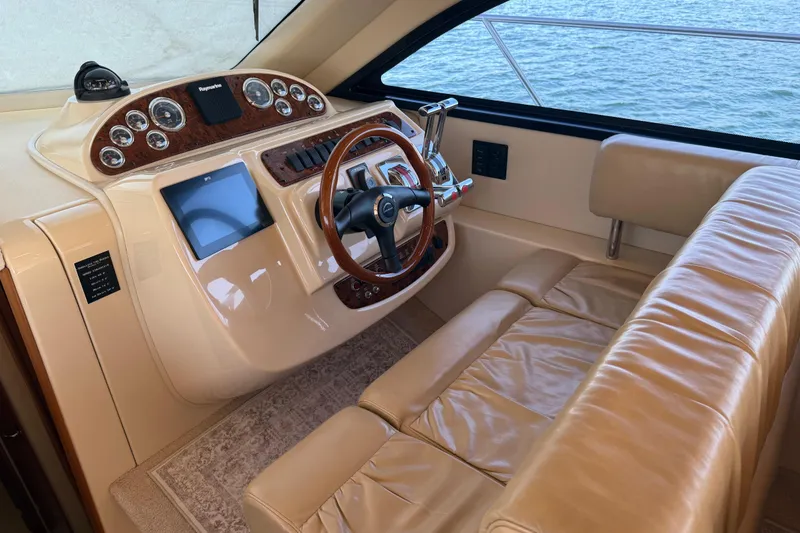 Slide: The Image of 2004 Meridian 411 Sedan helm with leather seating and wood-accented controls, overlooking water. - 28