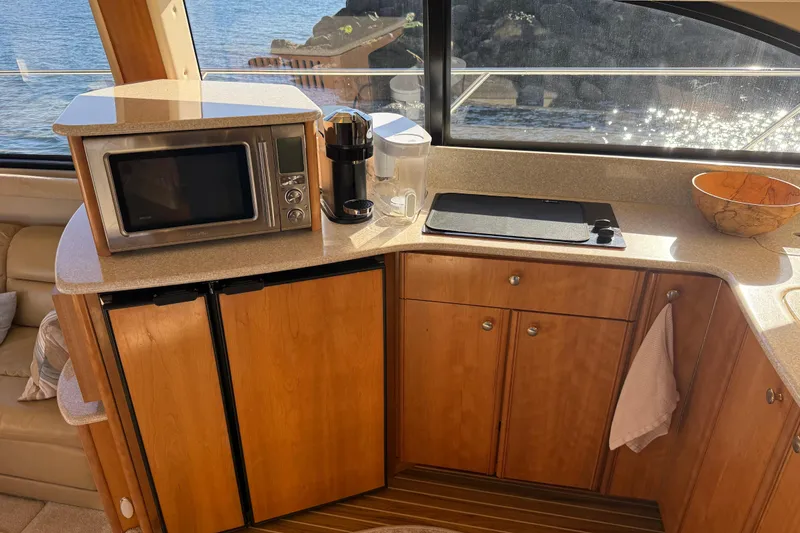 Slide: The Image of 2004 Meridian 411 Sedan kitchen with microwave, coffee maker, and wooden cabinets by a window. - 33