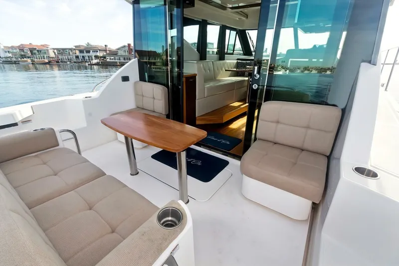 Slide: The Image of 2017 Tiara Yachts C39 Coupe interior with seating and table, overlooking waterfront homes. - 19