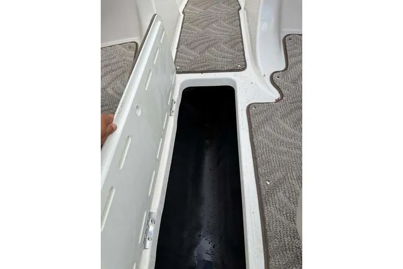 Slide: The Image of 2007 Glastron GXL 205 boat storage compartment with open hatch and carpeted flooring. - 11