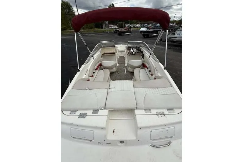 Slide: The Image of 2007 Glastron GXL 205 boat with red canopy and white seating, parked outdoors. - 7