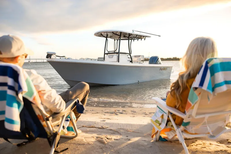 Slide: The Image of Couple relaxing on beach with 2026 Parker 230 Coastal Elite boat in the background. - 3