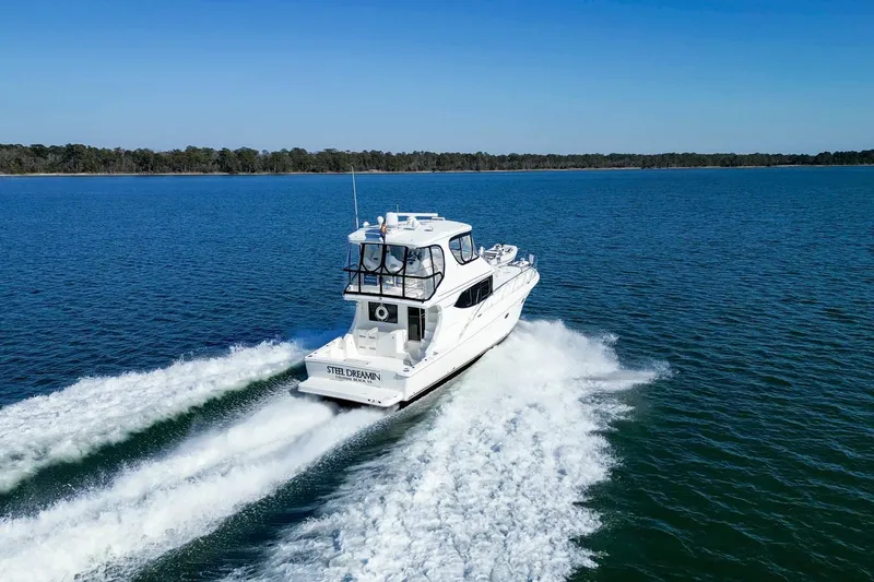 Slide: The Image of 2004 Silverton 48 Convertible yacht cruising on open water, clear blue sky. - 2