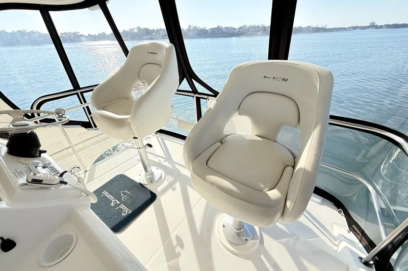 Slide: The Image of 2004 Silverton 48 Convertible yacht interior with two white captain chairs overlooking the water. - 21