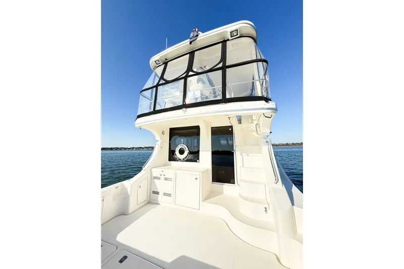 Slide: The Image of 2004 Silverton 48 Convertible yacht with spacious deck and flybridge, set against clear blue sky. - 22